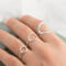 Hand with three open circle sterling silver rings (small, medium, large with hammered finish) on soft background.


